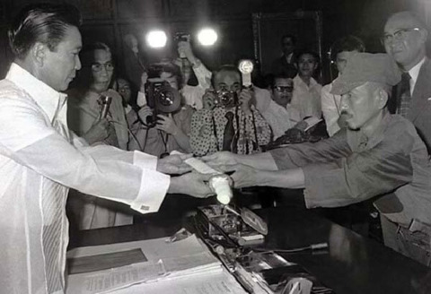 Hiroo Onoda finally surrenders his sword to Phillipine president Ferdinand Marcos, who probably immediately sold it to buy his wife more damn hell ass shoes.