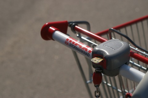 A typical shopping cart lock in Sweden with slots for 5 and 10 kr coins, with a token in the 10 kr slot.